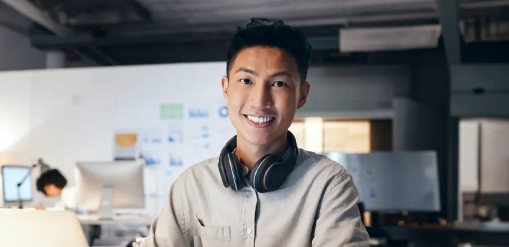 Estudiante sonriendo con unos auriculares negros.